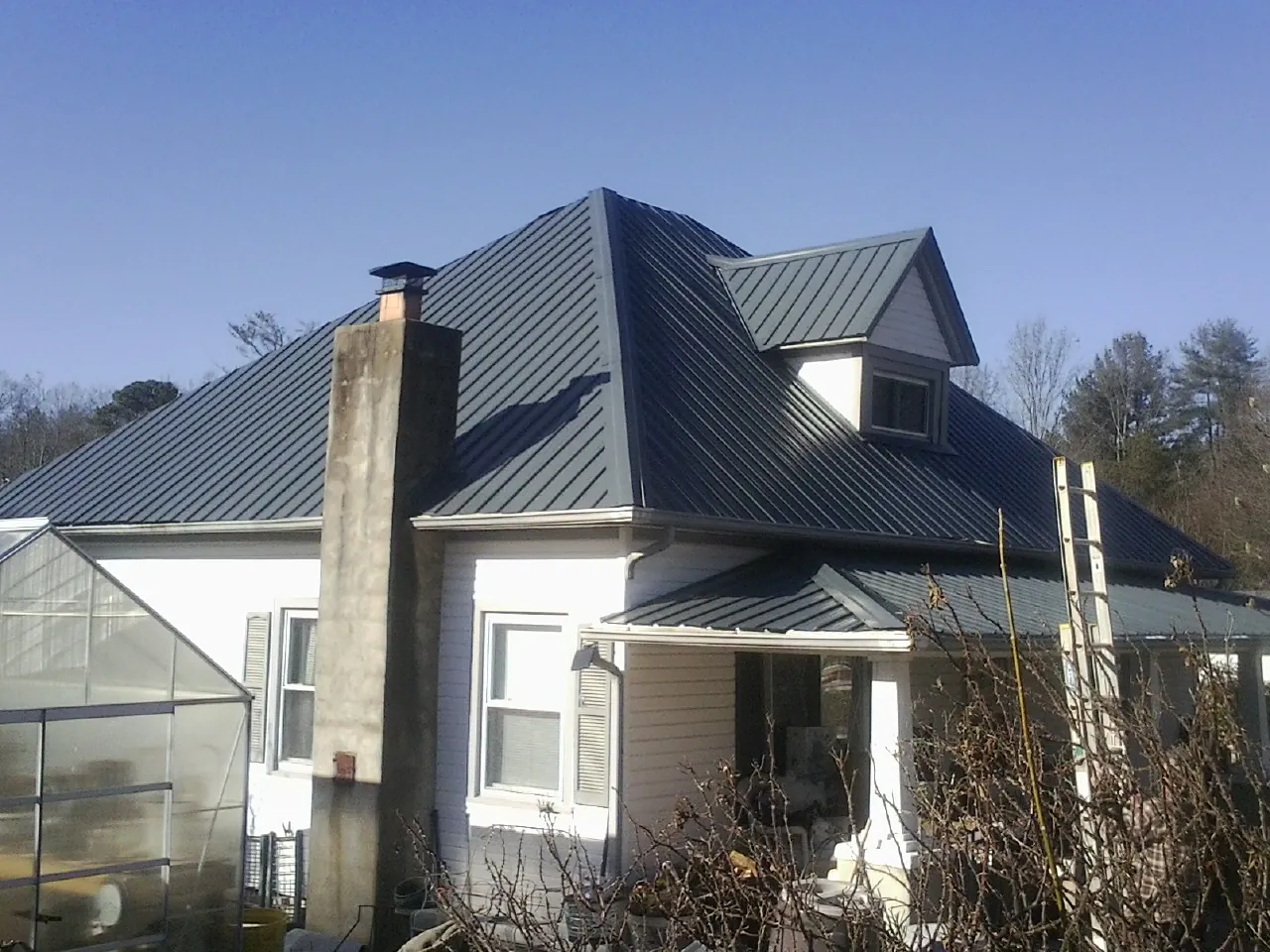 Dark blue standing seam metal roof on a white farmhouse with dormer — Slate & Tile Roof Repair by Roofing Brothers in Elbe