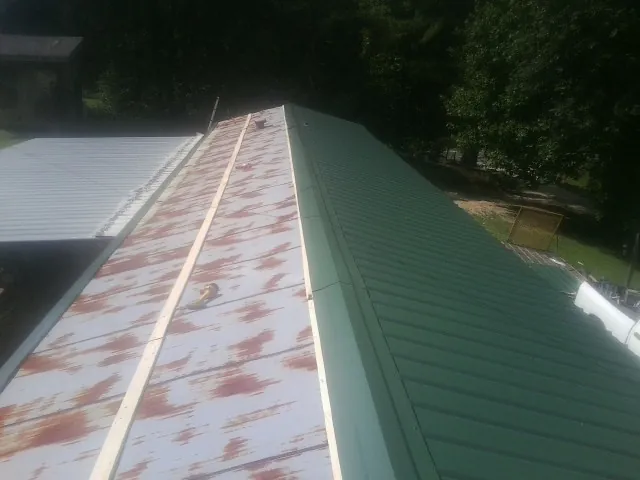 Old rusted panels beside newly installed green metal roofing — Wind Damage Roof Repair by Roofing Brothers in Elbe