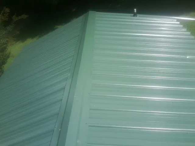 New green metal panels meeting at the ridge of a roof — Flat Roof Repair work by our crew in Elbe
