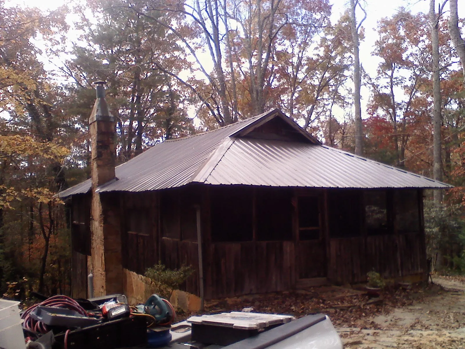 Brown metal hip roof on an old cabin with a stone chimney in Elbe