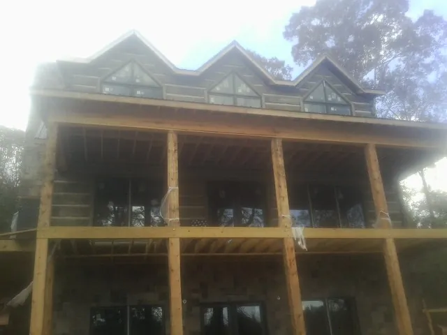 Dormers and porch framing on a large log home under construction — Roof Coating work by our crew in Elbe