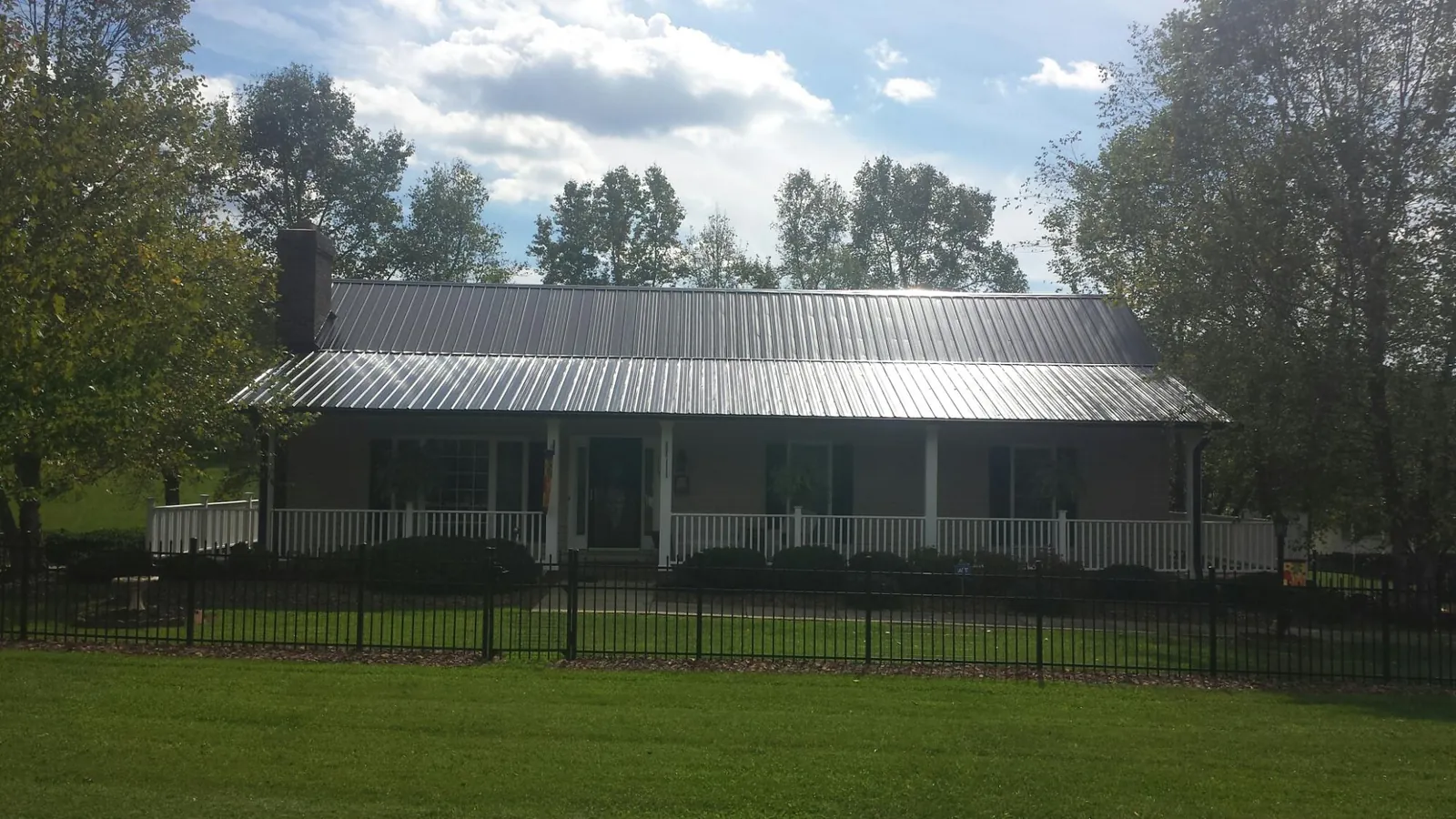 Gray metal roof on a brick ranch with a full width front porch — Gutter Guard Installation work by our crew in Elbe