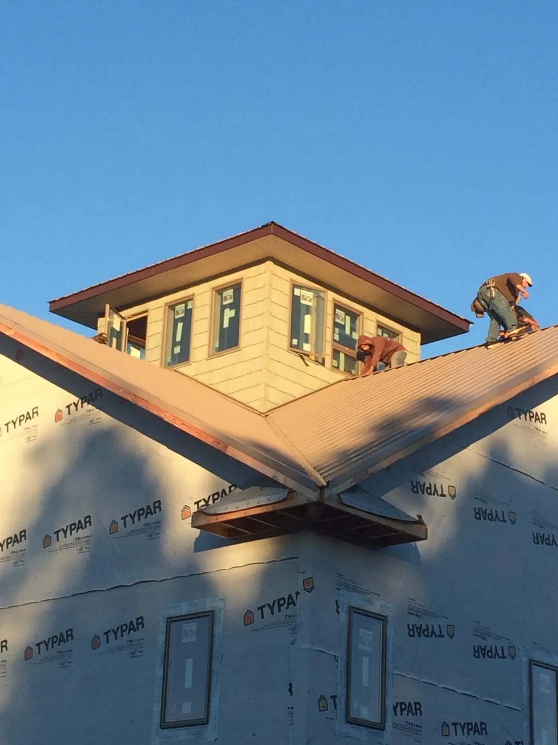 Roofers working around a rooftop cupola on a new metal roof at sunset — Roof Waterproofing in Elbe by Roofing Brothers